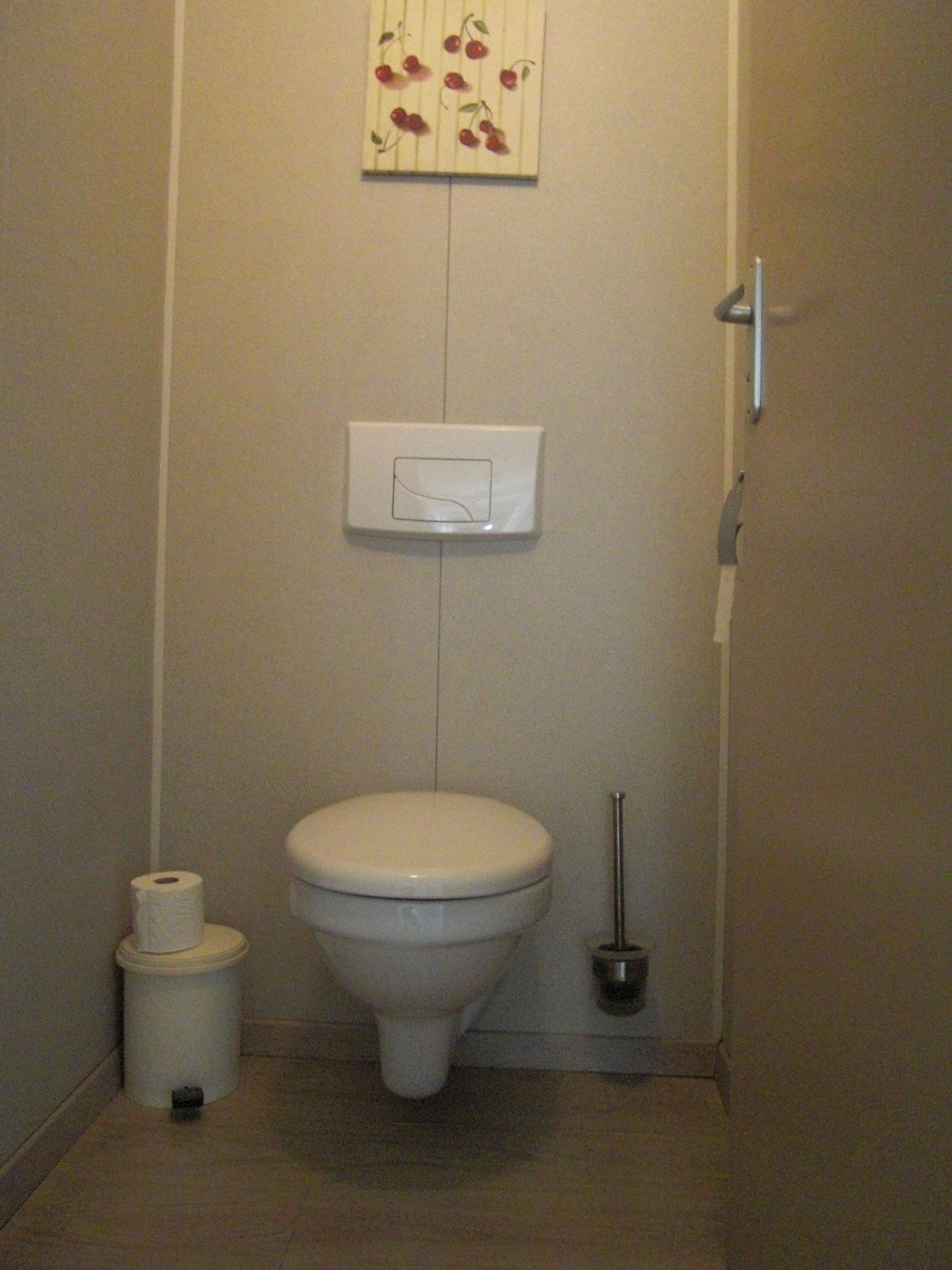 A small, compact bathroom with a toilet, a toilet paper holder, and a bidet.