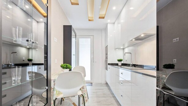 A modern kitchen with a glass backsplash, white cabinets, and a dining area with a table and chairs. - Luxurious apartment near Plaza Castilla, garage space. (Madrid)