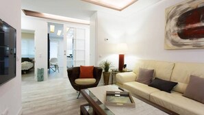 A modern living room with a sofa, armchair, and coffee table. There is a TV on the left and a painting on the wall. - Luxurious apartment near Plaza Castilla, garage space. (Madrid)