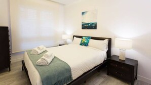 A hotel room with a bed, two bedside tables with lamps, a green throw blanket, and a painting on the wall. - Luxurious apartment near Plaza Castilla, garage space. (Madrid)