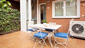 An outdoor patio with a table and chairs, a brick wall, a sliding glass door, and an air conditioning unit. - Luxurious apartment near Plaza Castilla, garage space. (Madrid)