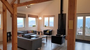 A spacious living room with a fireplace, large windows, and a view of the mountains. - Large, light and modern holiday home, beautiful view, beautifully situated (Ban-sur-Meurthe-Clefcy)