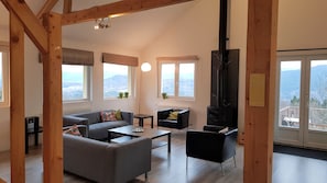 Un salon spacieux doté d’une cheminée, de grandes fenêtres et offrant une vue sur les montagnes.