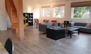 Un salon moderne avec un escalier, une bibliothèque, un canapé et une table basse.
