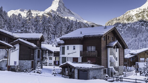 A snow-covered mountain resort with wooden buildings, including a sign that reads "Monte Cristo." - Chalet Monte Cristo (Zermatt)