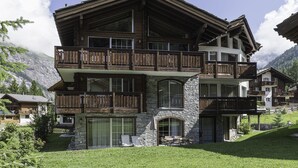 A multi-story chalet with wooden balconies, stone facade, and a view of the surrounding mountains. - Chalet Monte Cristo (Zermatt)