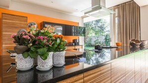 A modern kitchen with a black countertop, white patterned vases, and a view of the outdoors. - Houghton Place (Johannesburg)