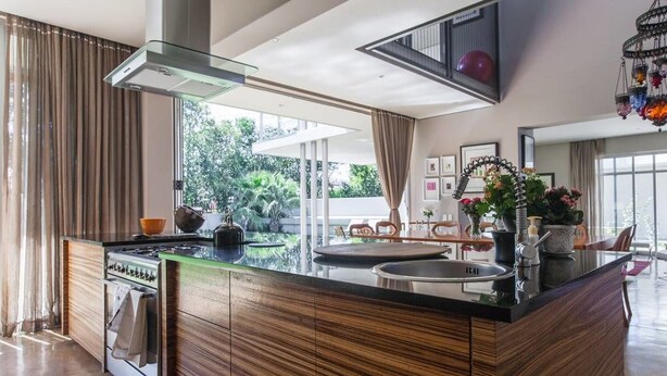 A modern kitchen with a central island, stainless steel appliances, and a large window providing a view of greenery outside. - Houghton Place (Johannesburg)