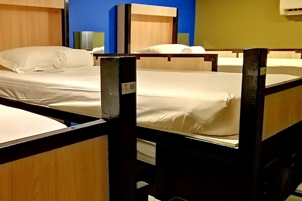 A hotel room with bunk beds, wooden headboards, and a blue wall.