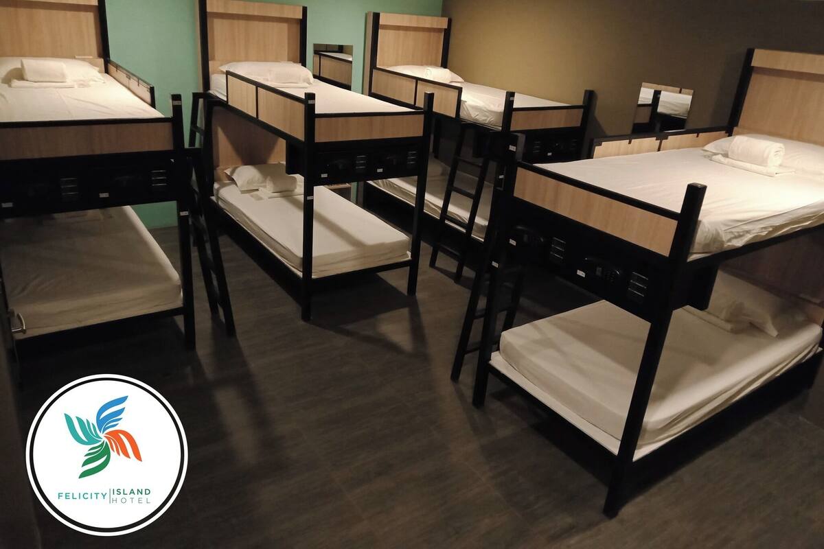 A hotel room with bunk beds, wooden headboards, and a green wall.
