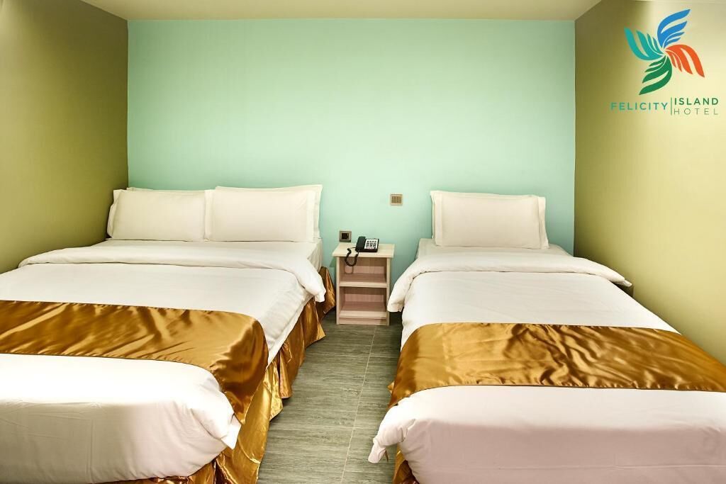 A hotel room with two beds, a nightstand, and a phone.