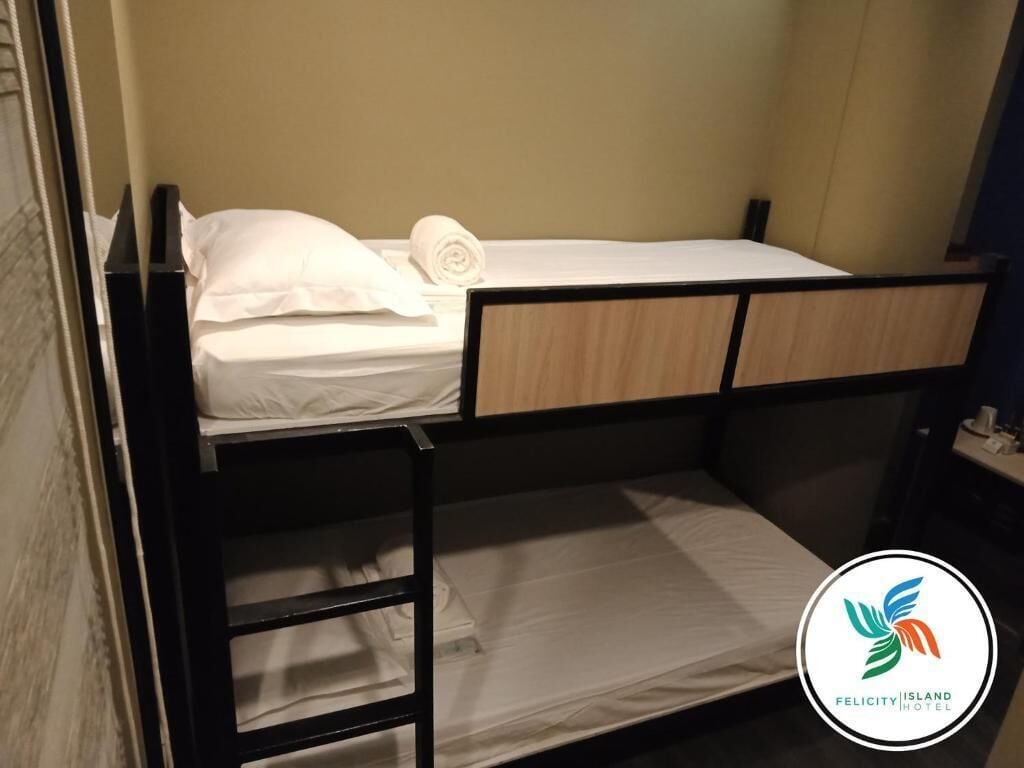Una cama litera con escalera, un almohadón blanco y una toalla enrollada en la parte superior.