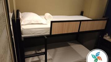 A bunk bed with a ladder, a white pillow, and a rolled towel on the top bunk.