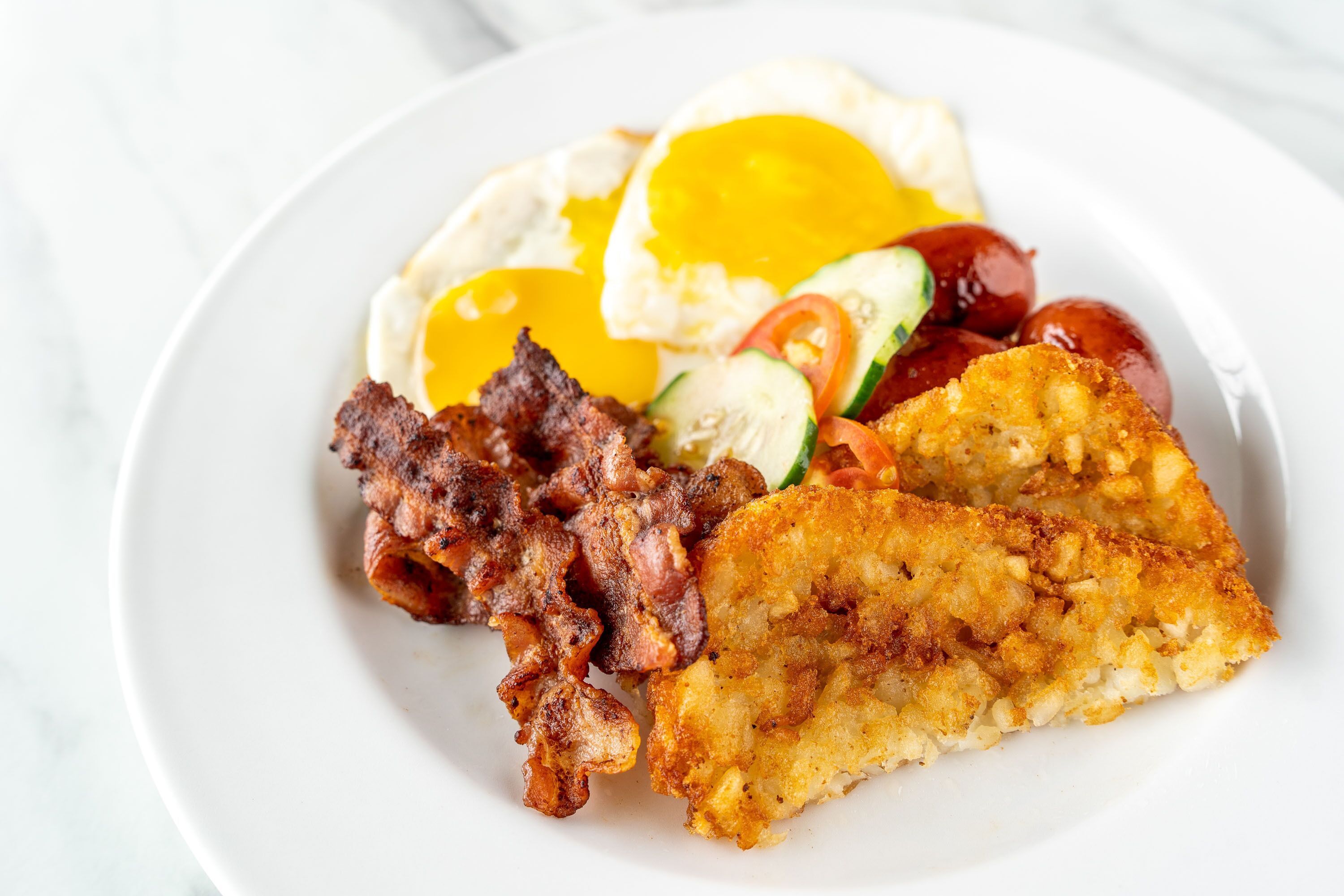 A plate of food with eggs, bacon, and a fried item.