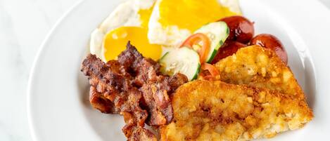 A plate of food with eggs, bacon, and a fried item.