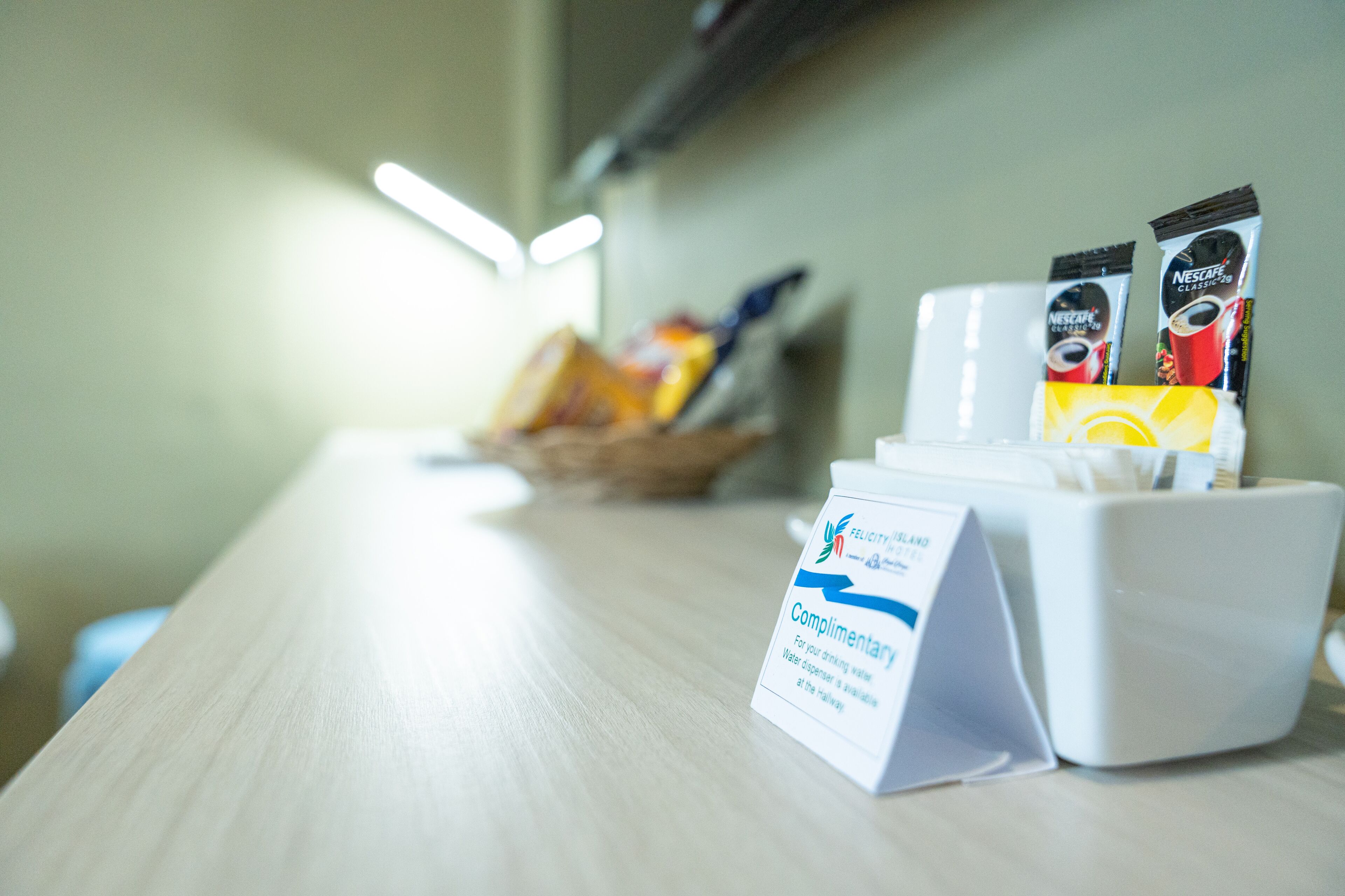 Dispensador de agua de cortesía sobre una mesa, con un cartel que indica su disponibilidad.