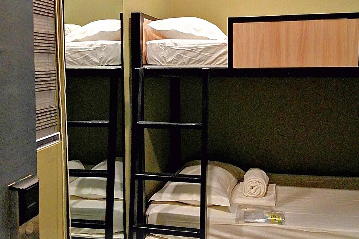 A bunk bed room with a wooden headboard, a small table with a bottle, and a towel on the lower bunk.