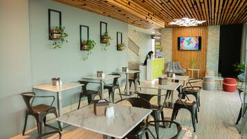 A modern cafe with wooden ceiling, black chairs, and tables.