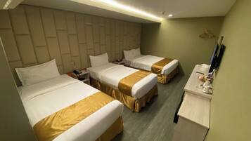 A hotel room with two beds, a desk, and a TV.