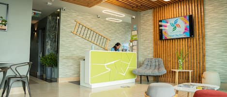 A modern reception area with a wooden ceiling, a reception desk, and a television displaying a colorful logo.