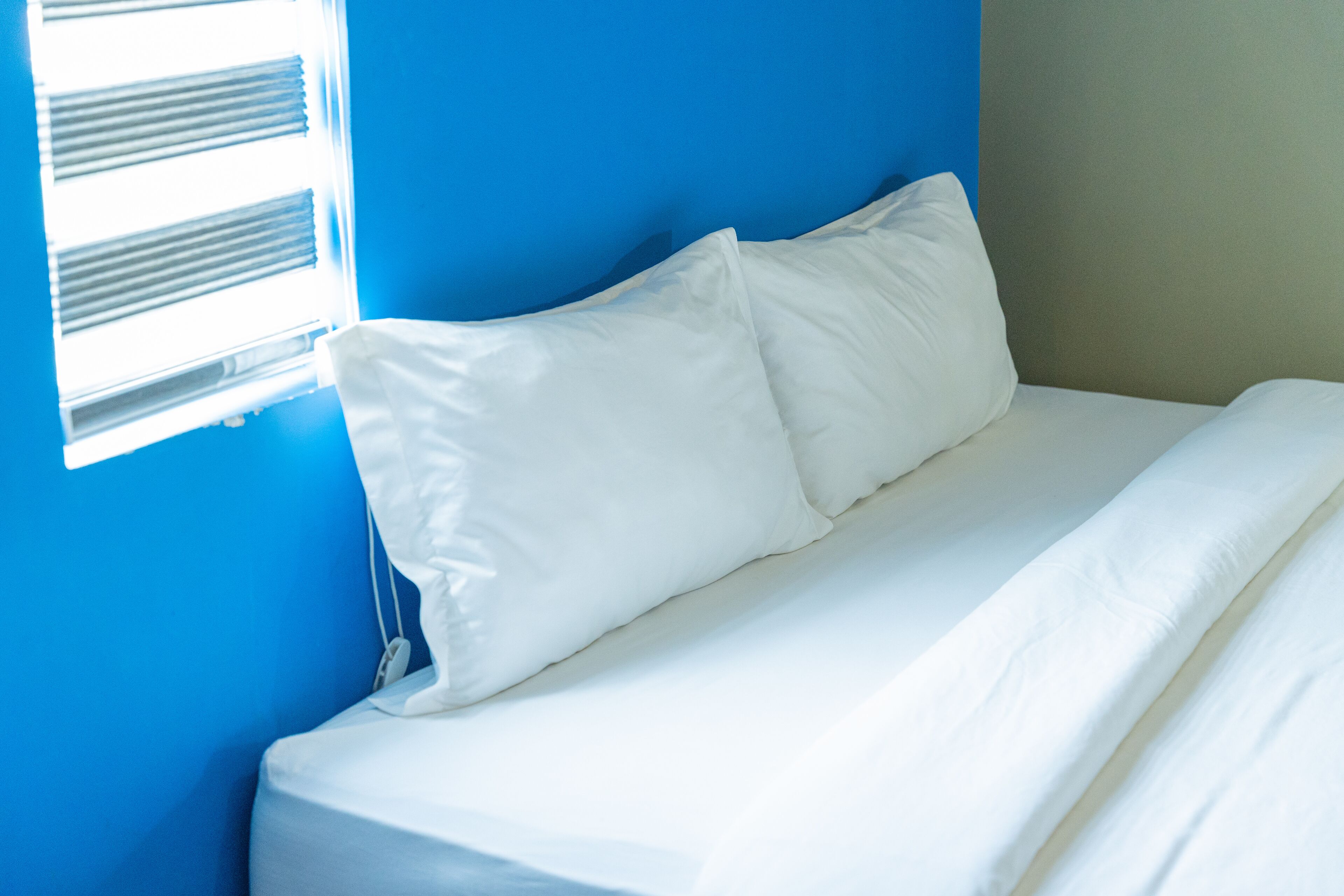 A bed with white bedding in a room with blue walls.