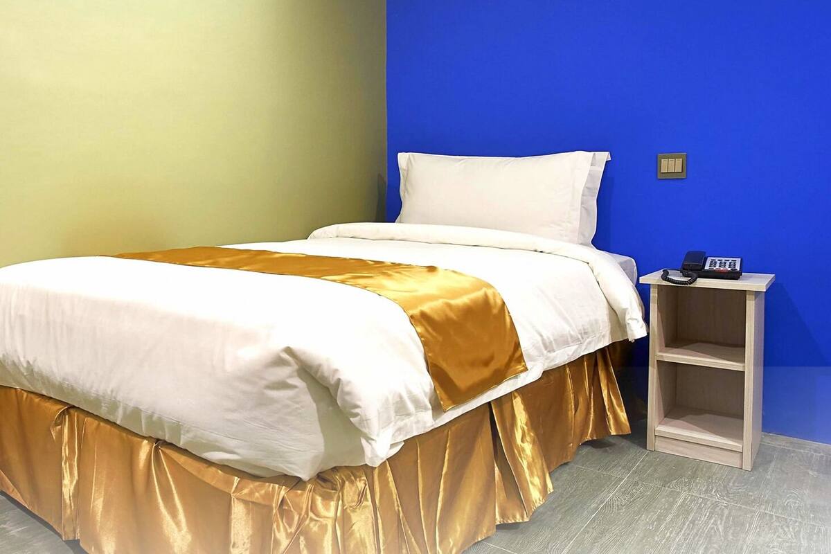 A hotel room with a bed, a nightstand, and a telephone.