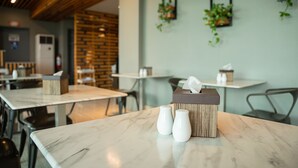A restaurant interior with marble tables, a wooden ceiling, and hanging plants. - Felicity Island Hotel (Lapu-Lapu)