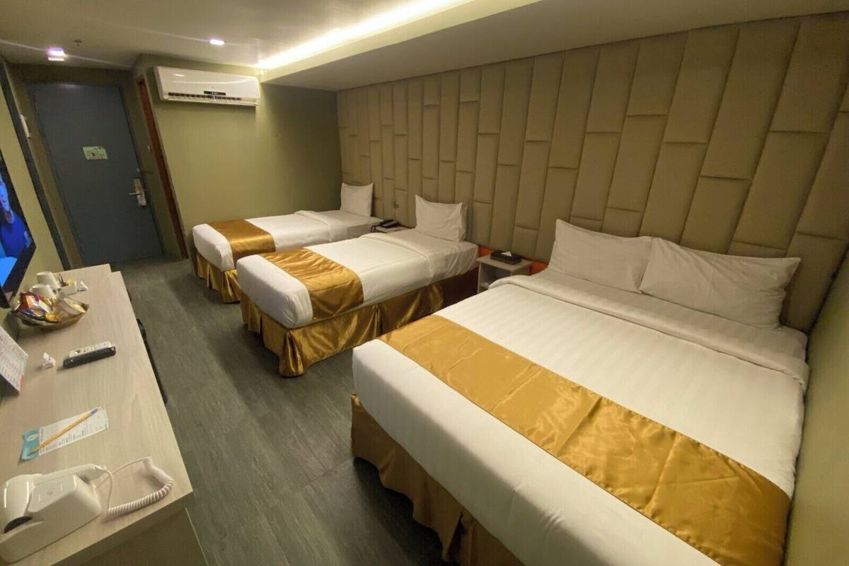 A hotel room with two single beds, a desk with a telephone, and a television.