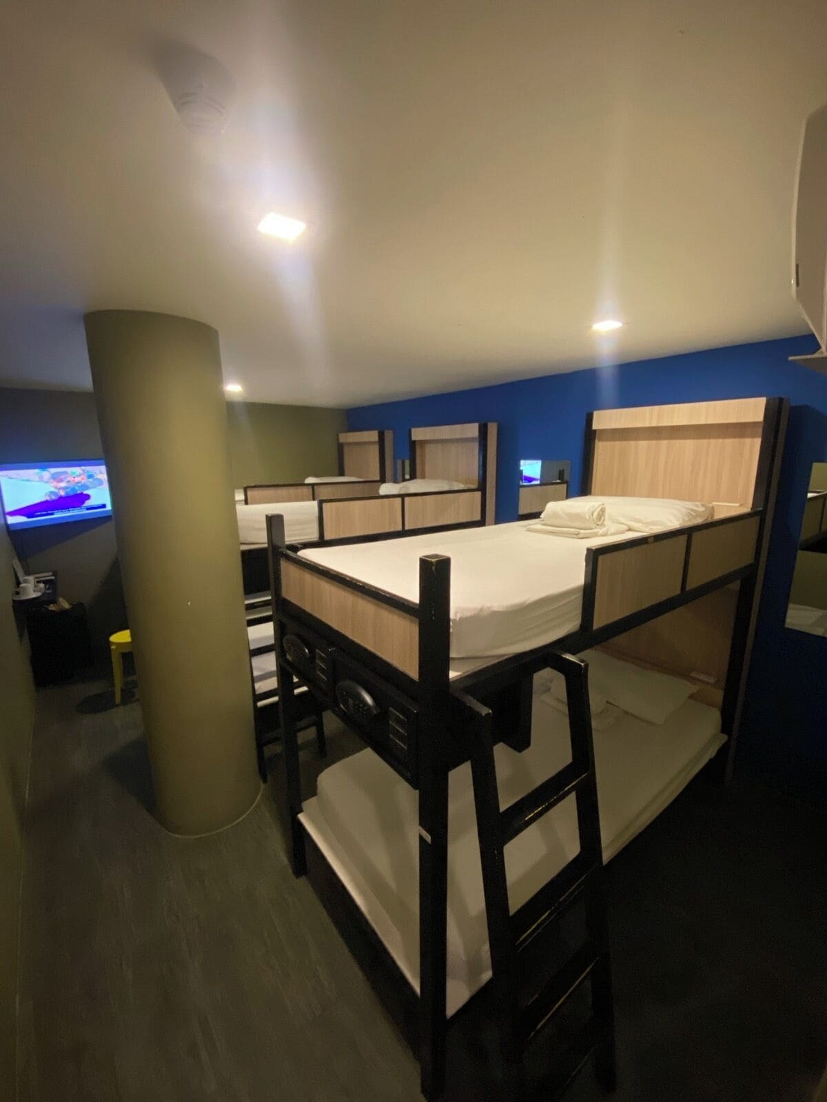 A bunk bed room with a television on the left, a small table, and a chair.