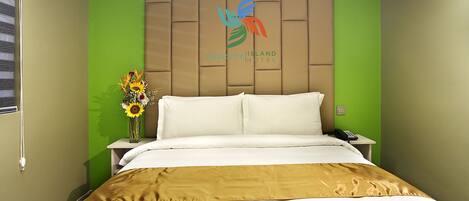 A hotel room with a bed, a nightstand, a vase with flowers, and a wall-mounted air conditioner.