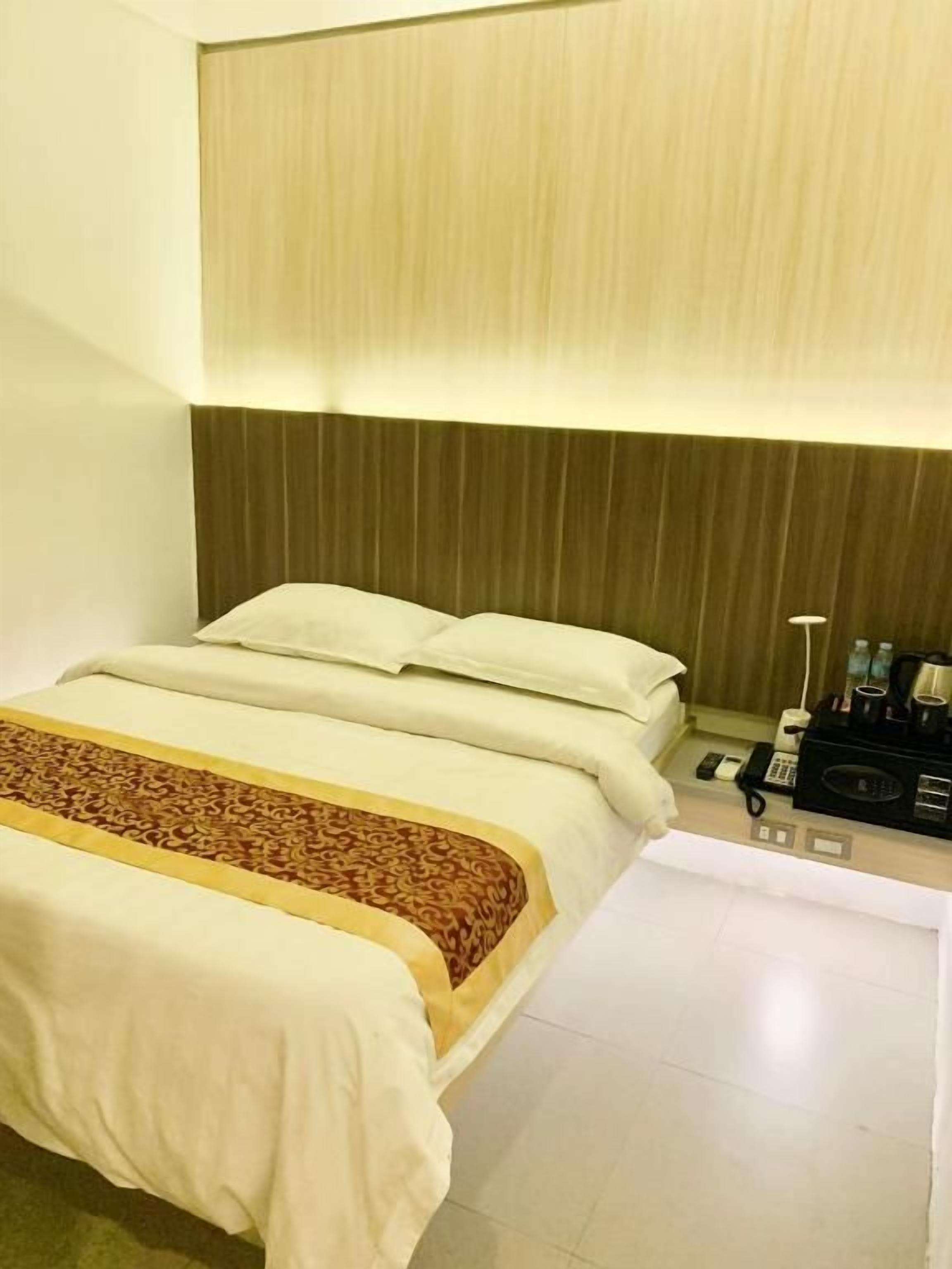 A hotel room with a bed, bedside table, and a lamp.