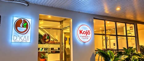 Entrada de hotel con señalización para D'Kae Coffee and Tea y Kojo Hotels Tagum.
