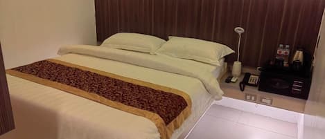 Una habitación de hotel con cama, mesita de noche, lámpara y panel de control.