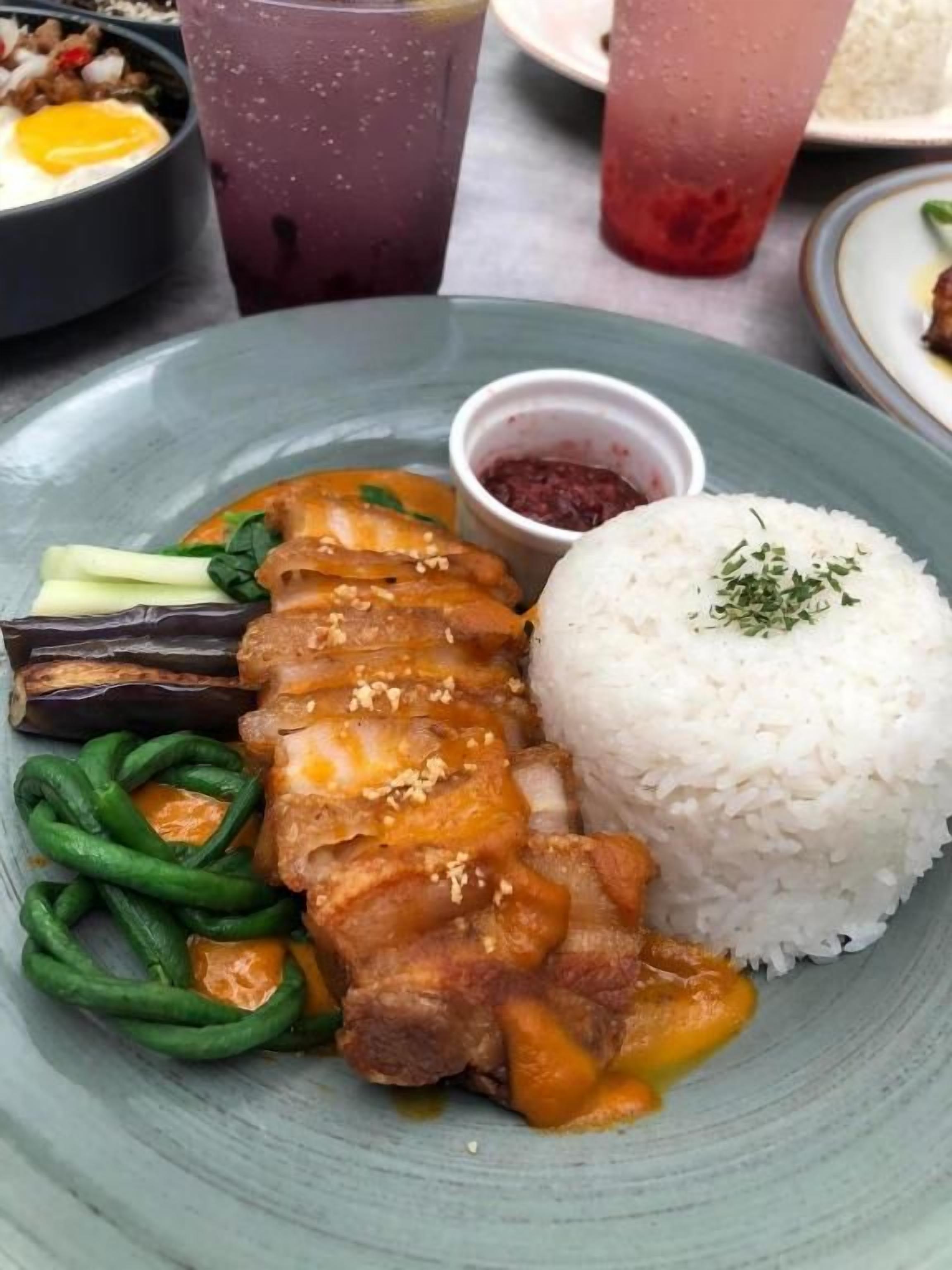 Un plato de arroz, carne a la parrilla, judías verdes y un recipiente pequeño con salsa.
