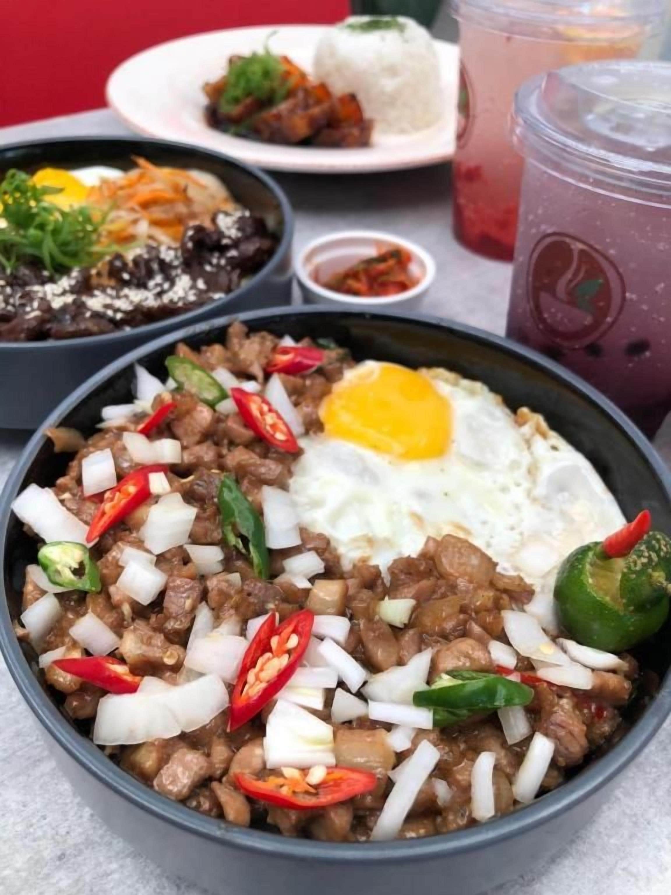 A bowl of food with a fried egg, meat, and vegetables.