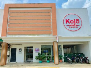 A hotel named Kojo Hotels-Tagum with a modern facade, a visible entrance, and several potted plants in front. - Kojo Hotel (Tagum)