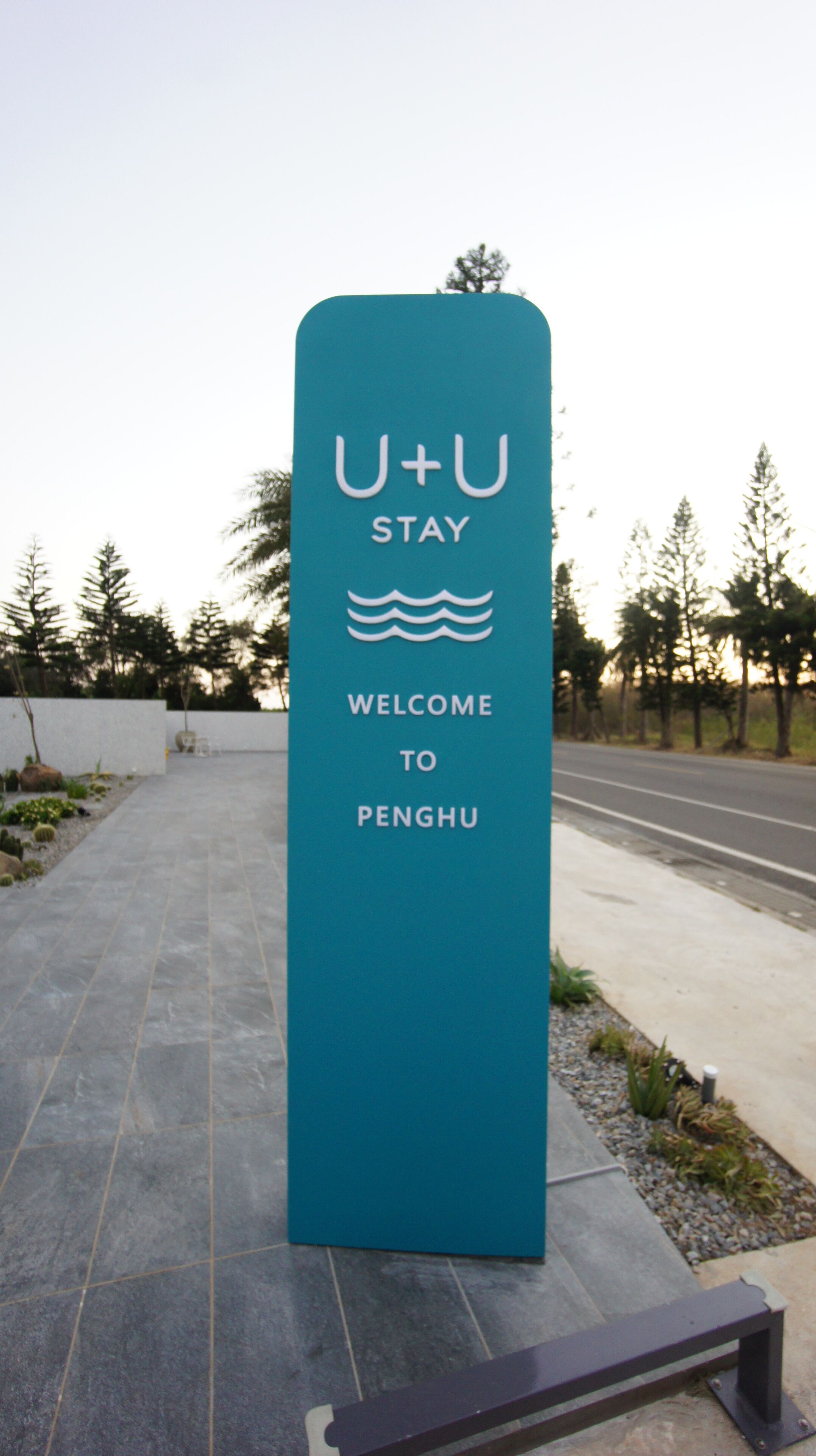Un letrero azul aguamarina de bienvenida para Penghu con 'U+U STAY' y un símbolo de ola.