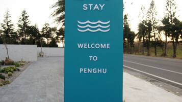 Un letrero azul aguamarina de bienvenida para Penghu con 'U+U STAY' y un símbolo de ola.