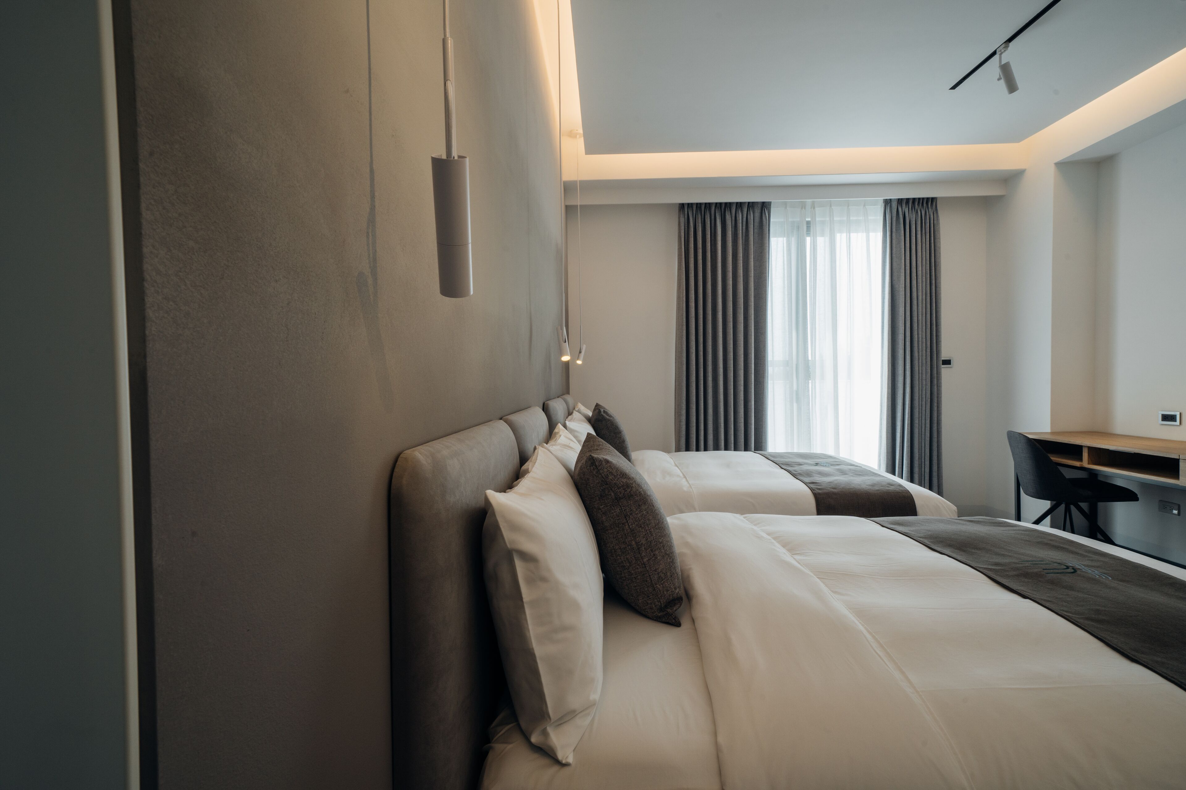 A modern hotel room with a large bed, a desk, and a view of the city.