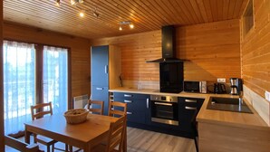 A modern kitchen with wooden cabinetry, a built-in oven, and a black range hood. - Welcome to Soleil, à la Neige, a pleasant family resort where life is good! (Eyne)