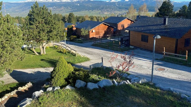 A rural setting with wooden cabins, a gravel driveway, and a mountainous backdrop. - Welcome to Soleil, à la Neige, a pleasant family resort where life is good! (Eyne)