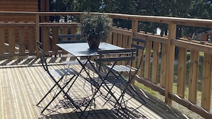A wooden deck with a table and chairs, surrounded by a wooden fence, and a potted plant in the center. - Welcome to Soleil, à la Neige, a pleasant family resort where life is good! (Eyne)
