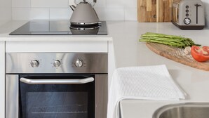 Une cuisine moderne équipée d’une bouilloire, d’un grille-pain et d’une planche à découper en bois avec des légumes.