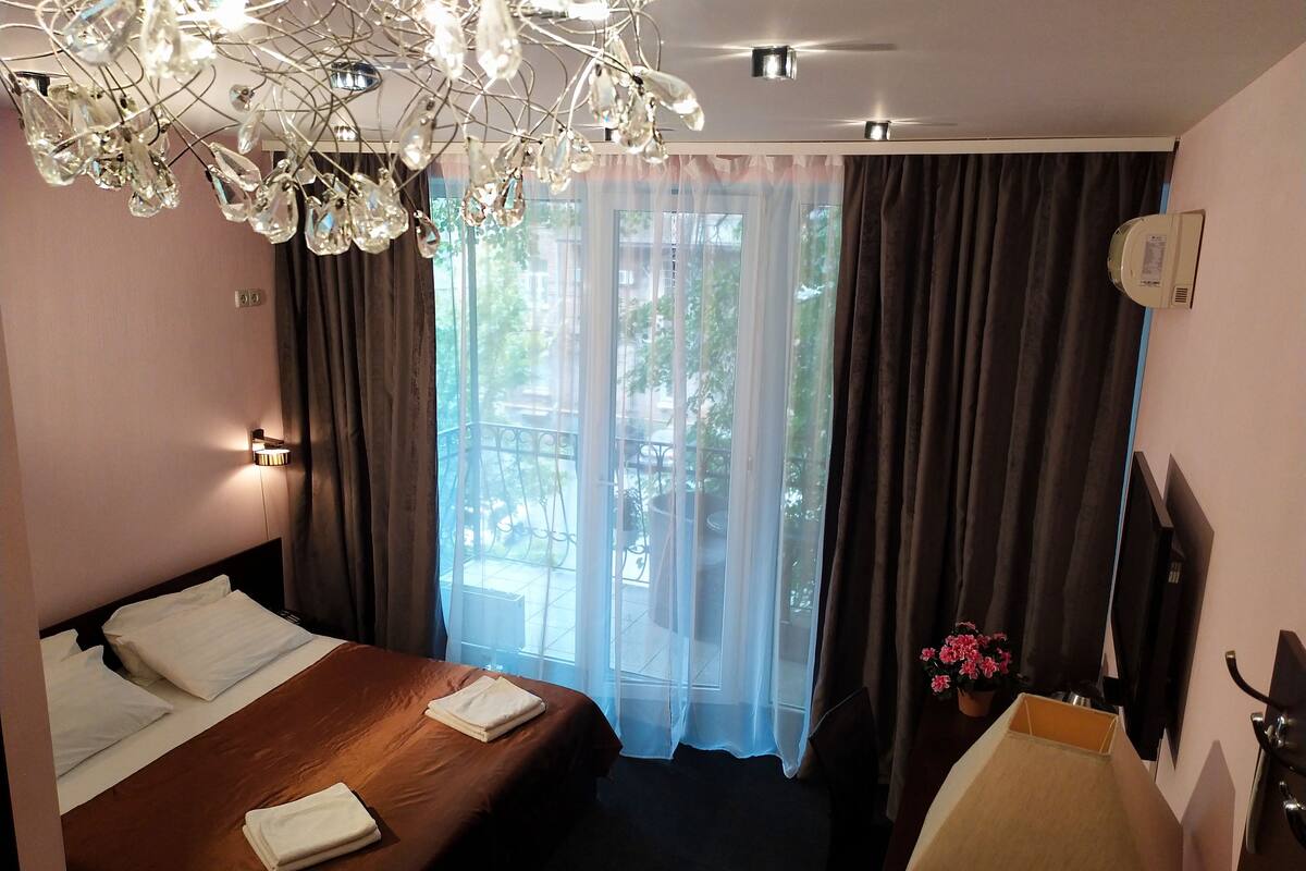 Una habitación de hotel con cama, baño, candelabro y vistas al exterior.