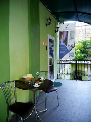 A green wall with a table and chairs, a QR code, and a sign for KIZHI HOTEL.