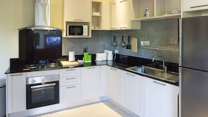 Una cocina moderna con armarios blancos, encimera negra, electrodomésticos de acero inoxidable y salpicadero de azulejos.