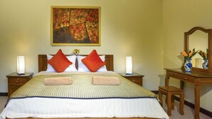 Habitación de hotel ordenada con una cama grande, dos lámparas de noche, una mesita de noche de madera, un aparador y un espejo.