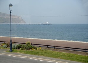 A coastal road with a lamp post, a beach, and a pier in the background.
