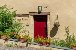 A building with a red door, a sign reading "Bienvenue," and potted plants in front. - Les Chambres d'Hotes - Le Vieux Nayeu (Raville)