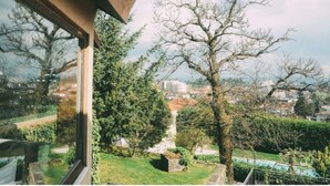 A view from a window overlooking a garden with trees and a distant cityscape. - Hotel Rural Quinta da Vista Alegre (Pacos De Ferreira)